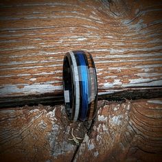 a ring with blue and white striped wood inlays sits on a piece of wood