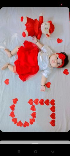 a baby laying on top of a bed with hearts drawn on the ground next to it