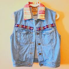 a blue jean vest hanging on a wall with a colorful scarf around it's neck