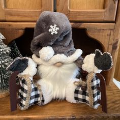 a stuffed animal is sitting in front of some christmas trees and other decorations on a shelf