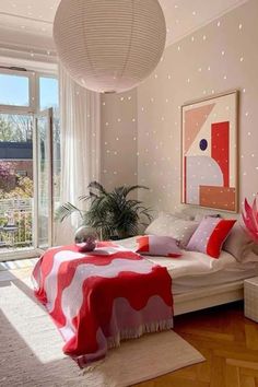 a bedroom decorated in red and white with lights on the ceiling, large window to outside