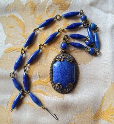 Unique and beautiful vintage art deco Czech blue art glass choker pendant. The brass link chain adorned with glass beads features a 1 inch wide 1.5 inch long statement sized dangle of cobalt blue glass set in an ornate filagree setting embellished with four blue cut crystals prong set and fastened with a delicate hook. At 16 inches, it calls for someone of slim neck. A truly spectacular antique piece of lovely patina and in excellent condition! An exquisite birthday, anniversary, special occasion antique jewelry gift idea.  Thanks for looking and please feel free to follow my shop and checkout my selection of authentic vintage jewelry finds!  https://avintagerendezvous.etsy.com Camphor Glass Jewelry, Edwardian Necklace, Czech Jewelry, Czech Glass Jewelry, Authentic Art, Cobalt Glass, Filigree Jewelry, Pendant Choker, Choker Pendant