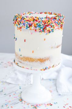 a white cake with sprinkles on it sitting on top of a table