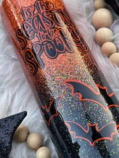 an orange and black glittered wine bottle sitting on top of a white fur covered floor