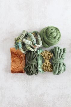 several different colored yarns are laid out on a white surface with a gold bag