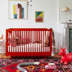 a baby's room with a red crib and toys on the floor