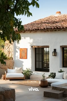 an outdoor living area with couches and potted plants in front of the house