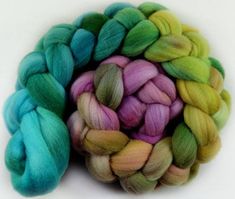 three skeins of dyed wool in different colors on a white surface, one is green and the other is blue