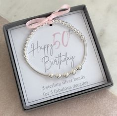 a birthday bracelet with pearls and pink ribbon in a gift box for someone's 50th