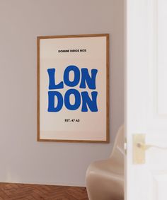 a framed poster hangs on the wall next to a chair in a room with hardwood flooring