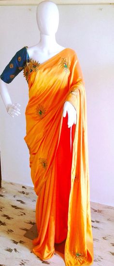 Orange semi raw silk saree with  hand embroidered peacock and unstitched blue green raw silk blouse Silk Traditional Wear With Dori Work In Orange, Orange Silk Traditional Wear With Dori Work, Orange Dola Silk Traditional Wear For Festivals, Orange Raw Silk Traditional Wear With Zari Work, Orange Embroidered Blouse Piece For Festivals, Festival Orange Embroidered Blouse Piece, Embroidered Orange Blouse Piece For Festivals, Orange Art Silk Blouse Piece With Resham Embroidery, Orange Saree With Dori Work