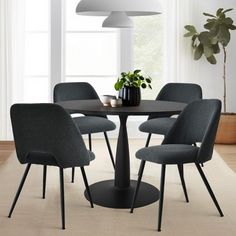 a table with four chairs around it in front of a window and potted plant