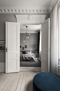 an open door leading into a bedroom with white walls and wood flooring on the side