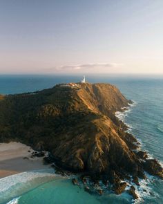 an aerial view of a lighthouse on the top of a hill next to the ocean