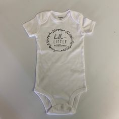 This is a white bodysuit that says Hello Little Wildflower.  Great for that little one of yours or for a gift! The designs we offer are created by hand, so please allow for slight variation in design placement. Please allow 3-7 business days for production.  Please feel free to contact me with any questions.  Thank you for shopping with us! Follow us on Facebook at facebook.com/williamandwesley.  To continue browsing graphic shirts, click here: https://www.etsy.com/shop/WilliamandWesley White Short Sleeve Onesie For Spring, White Short Sleeve Cotton Bodysuit, White Cotton Onesie As A Gift, Fitted White Short Sleeve Bodysuit With Letter Print, White Onesie For Summer Gift, White Onesie As Summer Gift, Summer Gift White Onesie, Cute White Short Sleeve Bodysuit, White Short Sleeve Bodysuit With Letter Print