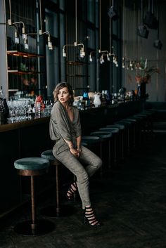 a woman sitting on a stool in front of a bar