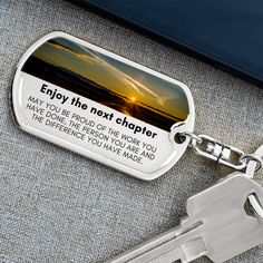 a keychain with a quote on it sitting next to a cell phone and keys