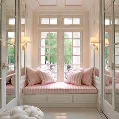 there is a window seat in the room with pink pillows on it and two windows