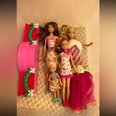 several dolls laying on top of a bed next to each other