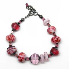 In the mood for pink?  Then this bracelet fits perfectly!  It features a selection of my handmade pink lampwork beads. The colors range from dark translucent pink, pink and purple frit beads, to light pink swirls.  These beads are simply stunning!   Such a beautiful combination for Spring!  The beads are strung along side sterling silver flower bead caps and pink Tourmaline rectangle shaped gemstone beads.   I have made the lampwork beads in this bracelet. The sterling silver has been oxidized t Pink Round Beaded Bracelets With Spacer Beads, Adjustable Pink Glass Bracelets, Adjustable Pink Bracelets, Pink Glass Beaded Bracelets As Gift, Pink Bracelets With Large Beads For Jewelry Making, Handmade Pink Glass Bracelets, Pink Glass Jewelry With Colorful Beads, Pink Czech Glass Beaded Bracelets With Colorful Beads, Pink Czech Glass Bracelets With Spacer Beads