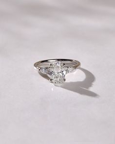 a three stone diamond ring sitting on top of a white surface with the light reflecting off it's side