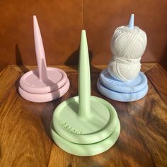 three different colored yarn holders on a table