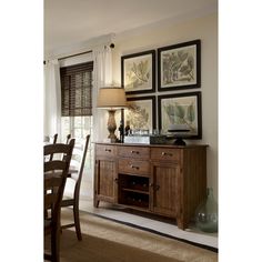 a dining room table and chairs with pictures on the wall above it in front of a window