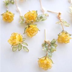 These handmade yellow rose dangle drop earrings are delicate and artistic in design. The earrings feature vibrant yellow rose blooms crafted from resin, which gives them a realistic, almost translucent appearance. The petals of the roses are meticulously shaped and layered to create a lifelike look. The leaves attached to the flowers are green, adding to the natural aesthetic.  The earrings have a drop length of around 30mm, making them dangle slightly below the earlobe. The pin that secures the earring to the ear is made of 925s silver,ensuring durability and a touch of elegance. The overall design is feminine and charming, perfect for adding a touch of floral beauty to any outfit. Cheap Yellow Flower Earrings For Gift, Bridal Drop Earrings, Flower Resin Jewelry, Natural Aesthetic, Resin Jewelry Diy, Metal Clay Jewelry, Earrings Resin, Spring Jewelry, Dope Jewelry