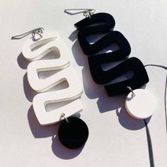 two pairs of black and white earrings sitting next to each other on top of a table