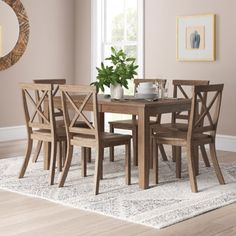 a dining room table and chairs in front of a round mirror on a rug with a potted plant