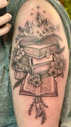 a tattoo with books and flowers on it