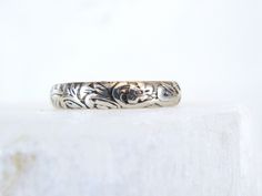 a silver ring sitting on top of a white surface