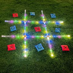 an illuminated tic - tac - toe game is shown on the grass with markers and lights