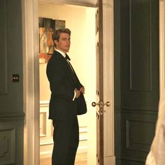 a man in a suit and tie standing in front of an open door