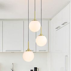 three lights hanging from the ceiling in a kitchen