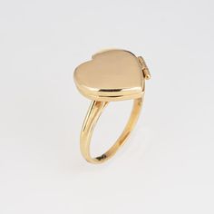 This is part of Chairish’s Fine Jewelry assortment.  Stylish picture locket ring crafted in 14 karat yellow gold.   The heart shaped ring is a wonderful sentimental piece. The locket opens to reveal two sections that can accommodate a picture or keepsake. The low rise ring (5mm - 0.19 inches) sits comfortably on the finger.  The ring is in very good condition and was recently professionally cleaned and polished.   Particulars:  Weight: 3.3 grams  Stones:  N/A   Size & Measurements: The ring is a Yellow Gold Oval Heart Ring For Valentine's Day, Engraved Heart-shaped Yellow Gold Ring, Engraved Heart Shaped Yellow Gold Ring, Yellow Gold Heart-shaped Engraved Ring, Yellow Gold Heart-shaped Engraved Ring Stamped 14k, Heart-shaped Yellow Gold Signet Ring For Wedding, Heart Shaped Yellow Gold Signet Ring For Anniversary, Heart Shaped Yellow Gold Signet Ring For Wedding, Heart-shaped Engraved Yellow Gold Ring Stamped 14k