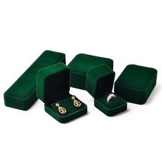 three green velvet jewelry boxes with gold rings