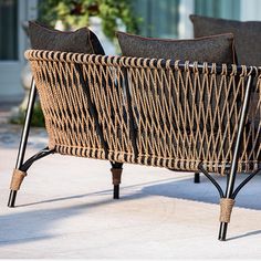 two wicker chairs sitting next to each other on a patio with black cushions and metal legs