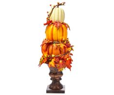 a decorative arrangement of pumpkins and gourds on a pedestal with autumn leaves