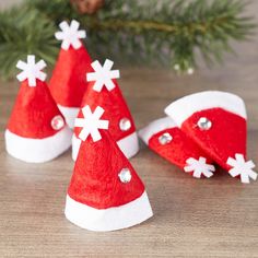 three red and white christmas hats sitting on top of a wooden table