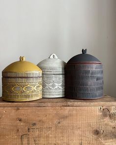 three ceramic containers sitting on top of a wooden table