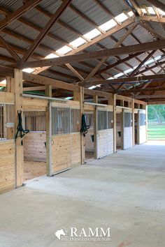 the inside of a horse barn with wooden stalls and stalls on either side of it