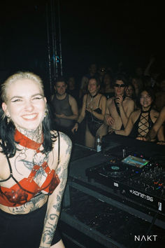 a woman with tattoos standing in front of a dj set