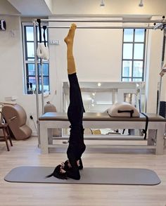 a person doing a handstand on a yoga mat in a room with benches