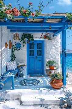 a blue and white house with potted plants on the porch