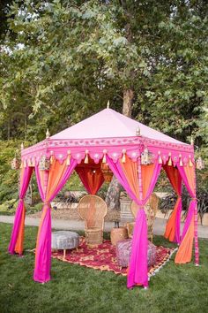 a pink and orange tent sitting on top of a lush green field