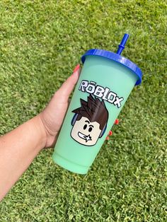 a hand holding a green starbucks cup with roblox on it and a blue lid