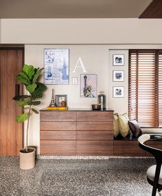 a living room with wooden furniture and pictures on the wall above it, along with a potted plant