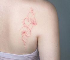 the back of a woman's shoulder with pink flowers on her left arm and an outline of a butterfly