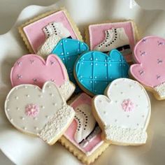 decorated cookies in the shape of mittens and gloves on a white plate with pink and blue frosting